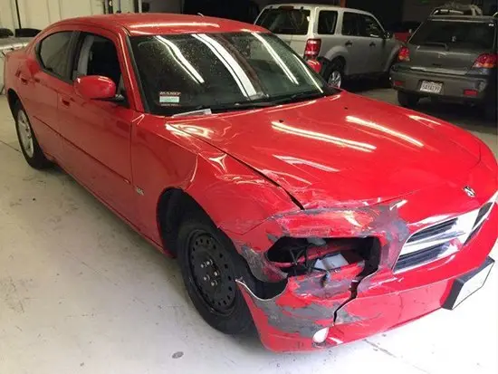 Damaged red sedan before repair