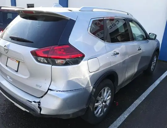Damaged white SUV before rear-end repair