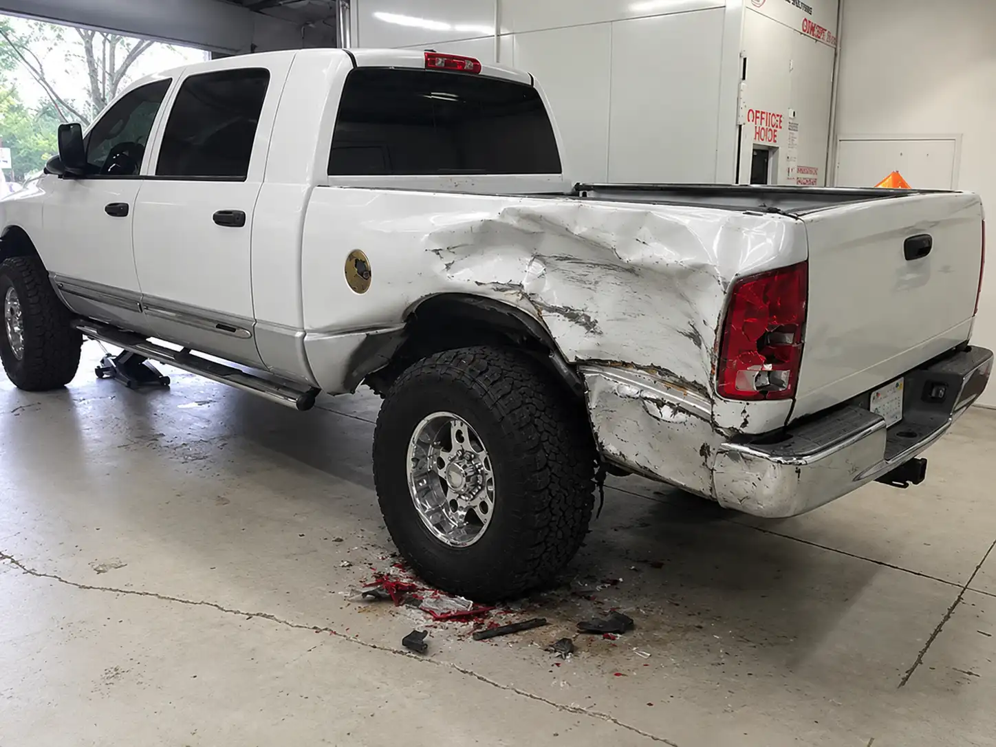 White pickup truck with a crushed bed side, rear fender and tail light